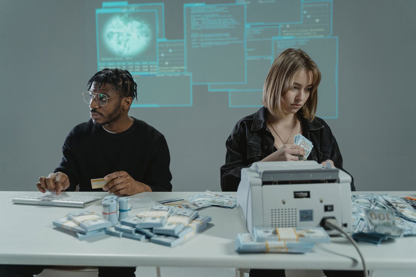 Two individuals counting US dollar bills with