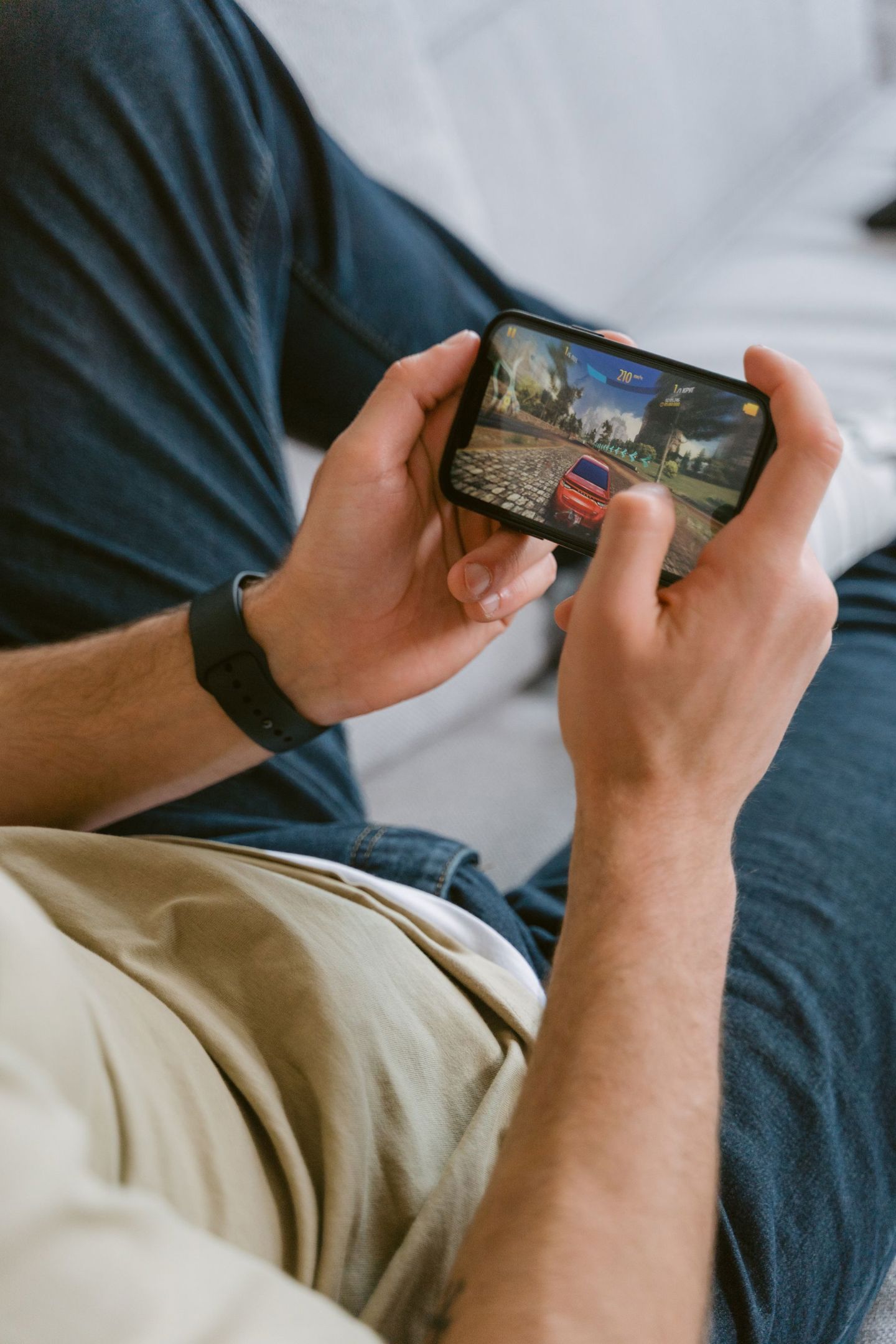 A young adult playing a racing game on a smar