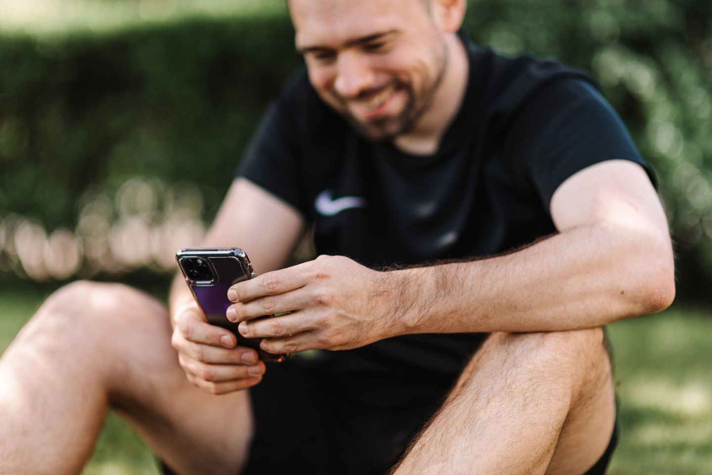 A smiling man wearing a black shirt uses a sm