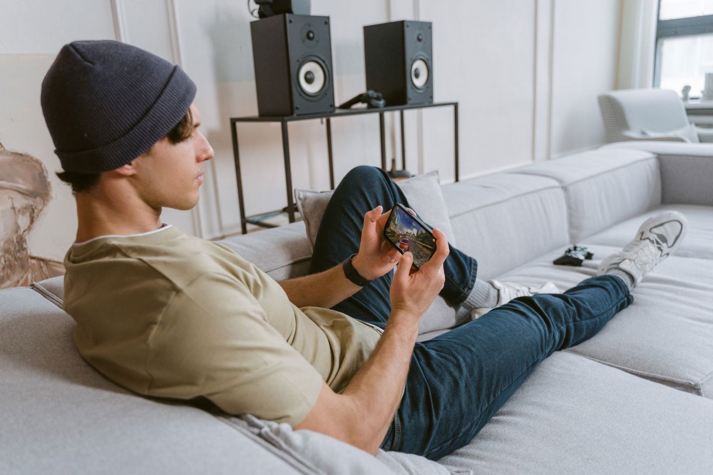 Casual young man playing mobile games on sofa