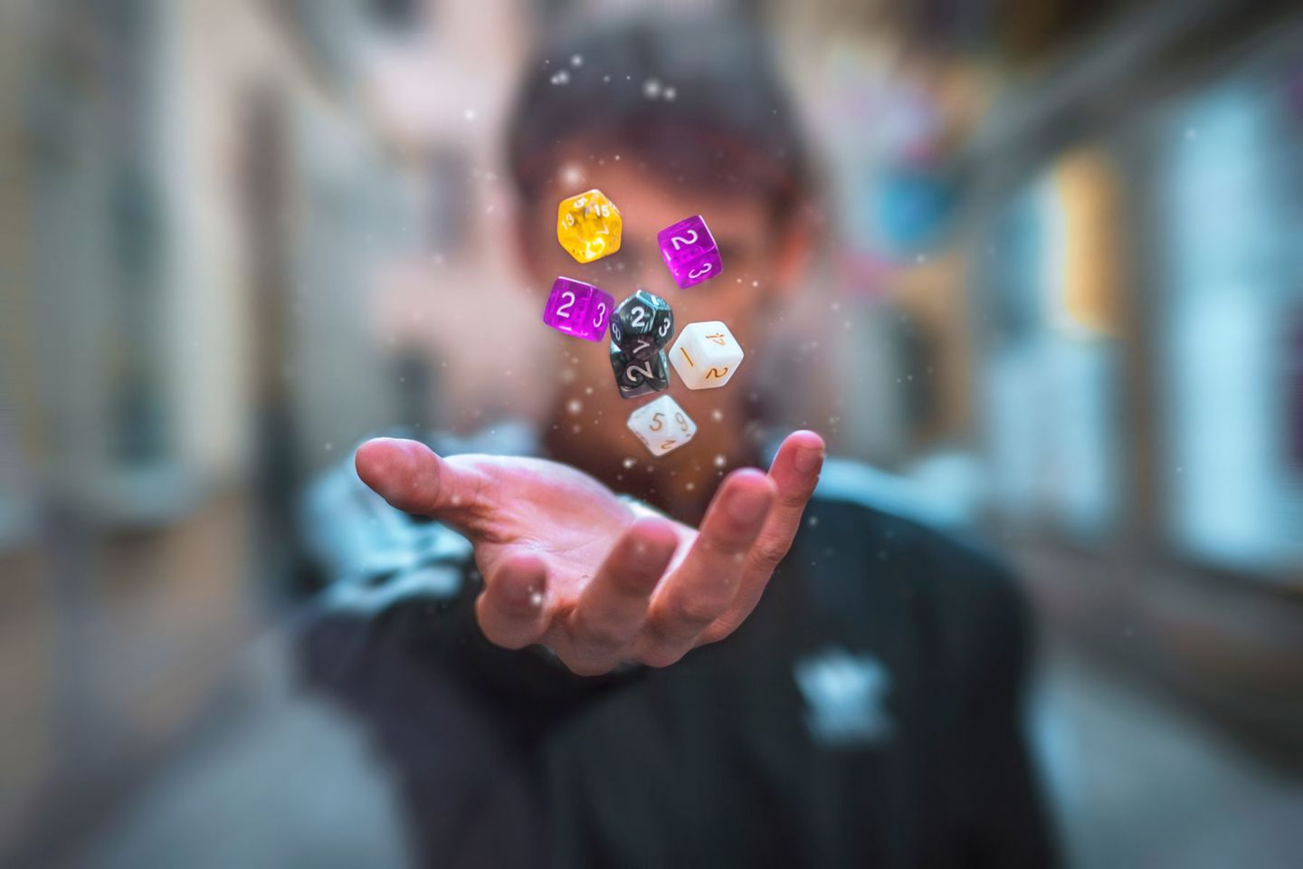 Colorful dice float above a hand with a blurr